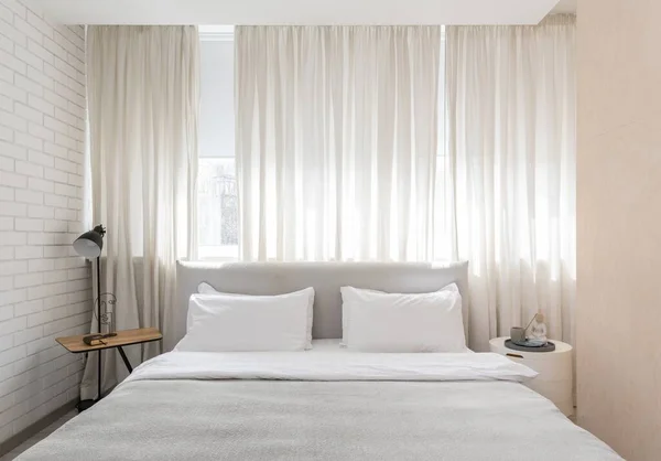 Nahaufnahme des Schlafzimmers mit weißer Bettwäsche auf dem Bett und Couchtisch mit Lampe — Stockfoto