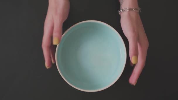 Womens hands with yellow manicure correct a blue plate on a black background — Stock Video