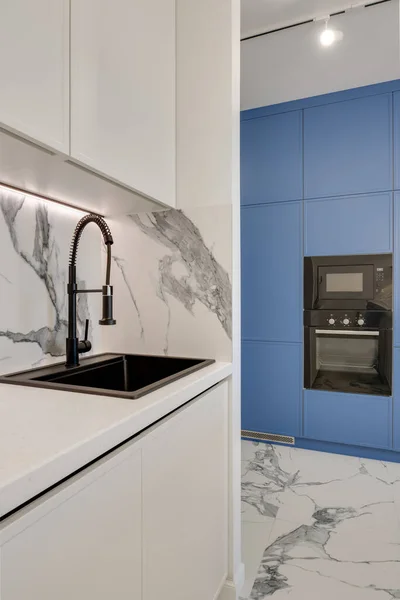 Element i ett ljust kök med blå möbler, svart ugn och svart kran — Stockfoto