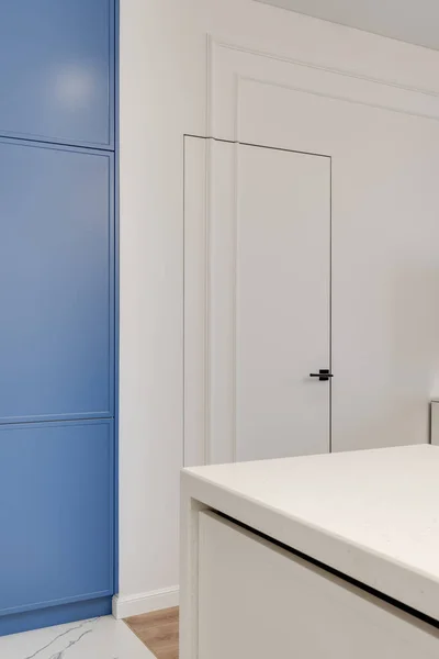 Närbild av ett inredningselement med vit vägg och dörr och blått skåp — Stockfoto