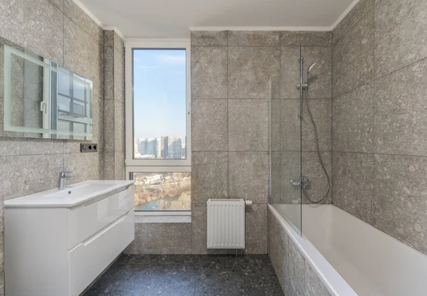  Geniş pencereli tuvalet, tuvalet ve aynalı lavabo.