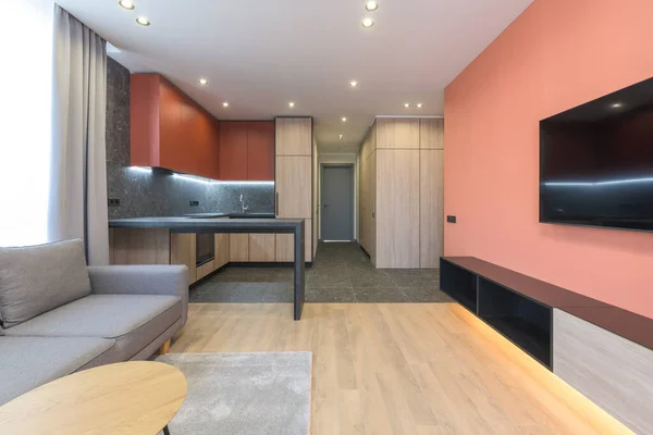 Modern design av en bostadslägenhet med Marsala-färgade väggar, en grå soffa och ett träkök — Stockfoto