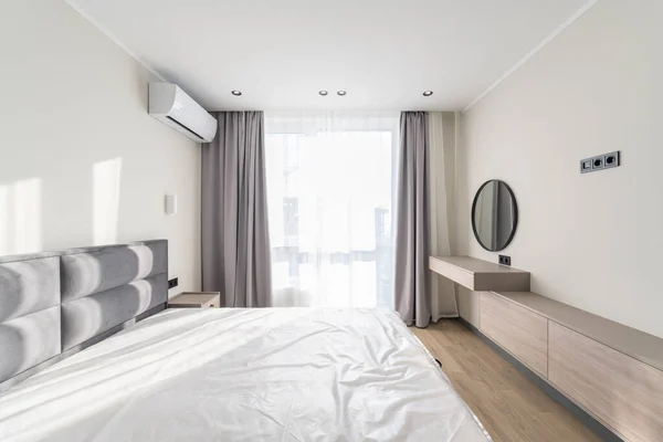 Wide corner of the bedroom in a modern style with a large bed, window, air conditioning and a round mirror — Foto Stock