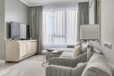 Penceresinin yanında büyük televizyonu olan gri oturma odası