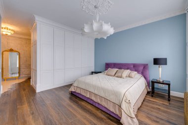 Büyük bir pencerenin yanındaki mavi bir odada büyük mor bir yatak. Önde cam bir bölme var. Yüksek kalite fotoğraf