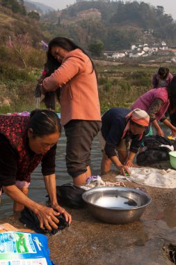 Yunnan, Çin - 1 Mart 2012: Çinli kadınlar eski bir köyün yakınlarındaki eski bir umumi çamaşırhanede yıkanırken duş alıyorlar. Yunnan..