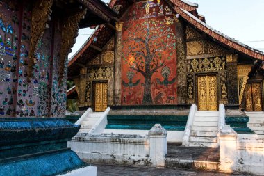 Wat Xieng Tangası 'ndaki antik Budist tapınağının pitoresk dış görünüşü, altın tablolar, duvarlarda boyalı cam süslemeler ve ahşap kapılar. Luang Prabang, Laos. Tapınak halka açık..