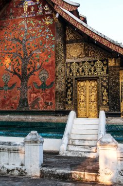 Wat Xieng Tangası 'ndaki antik Budist tapınağının pitoresk dış görünüşü, altın tablolar, duvarlarda boyalı cam süslemeler ve ahşap kapılar. Luang Prabang, Laos. Tapınak halka açık..