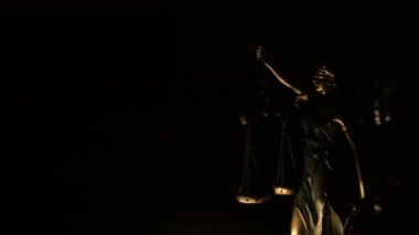 Bir mumla aydınlatılmış Adaletin Hanımı figürü.
