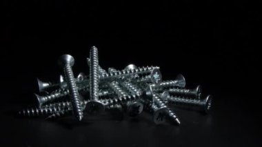 Siyah arka planda dönen endüstriyel metal vidalar.