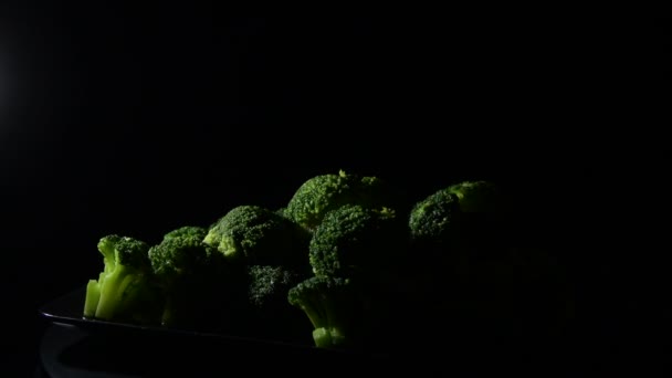 Brócoli Fresco Girando Sobre Una Bandeja Negra Con Fondo Negro — Vídeos de Stock
