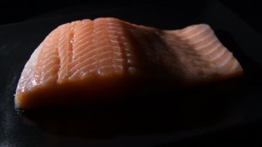 Fresh salmon steak on a black tray gyrating