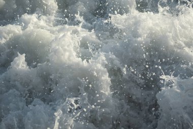 Gün batımında dalgalı denizde beyaz köpük