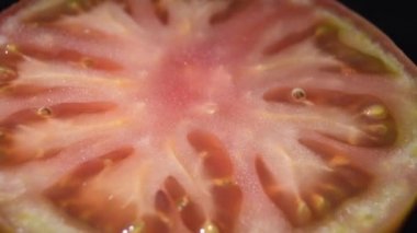 Olgun kırmızı domates siyah arkaplanda dönüyor.