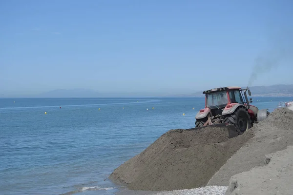 Tractor machine moving sand in works of regeneration of beaches