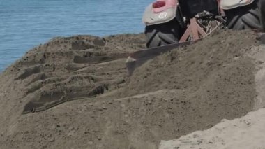 Traktör kumsaldaki kumu nipeliyor.