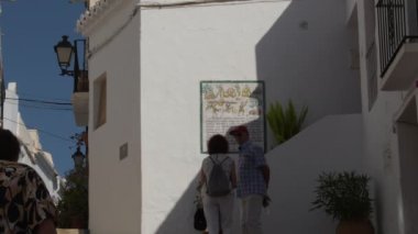 Tourists walking in a andalusian whitewashed street at sunset, Frigiliana, Spain