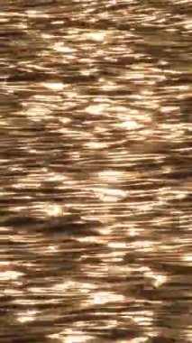 Güneşin günbatımında denizin dalgalarına yansıması. Dikey 4K