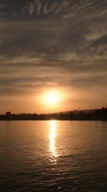 Gün batımında güneş, gökyüzü ve deniz dalgaları. 4K Dikey