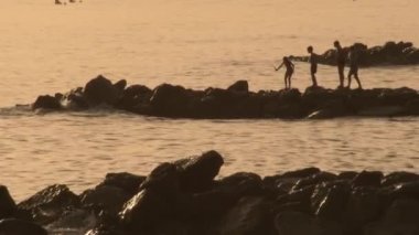 Gün batımında kayalıklarda oynayan çocuklar.