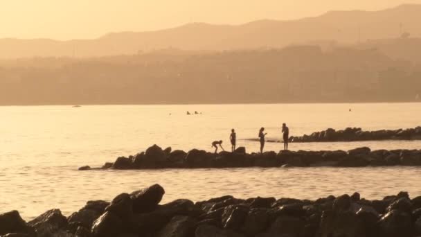 夕暮れ時に小さなビーチの岩で遊んでいる子供たち — ストック動画