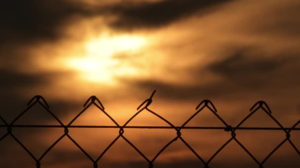 夕阳西下的铁丝篱笆中的云彩间的太阳 — 图库视频影像