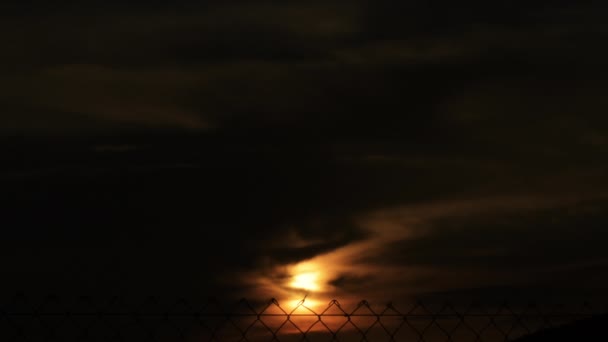 ワイヤーフェンスで日没時の雲の間の太陽 — ストック動画