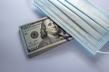 Amerika Birleşik Devletleri banknotları ve virüse karşı koruyucu bir maske. Coronovirüs ile ilişkili dünya ekonomik krizi.