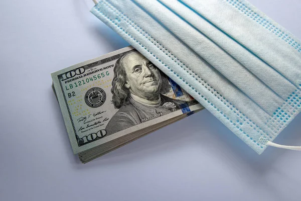 Amerika Birleşik Devletleri banknotları ve virüse karşı koruyucu bir maske. Coronovirüs ile ilişkili dünya ekonomik krizi.