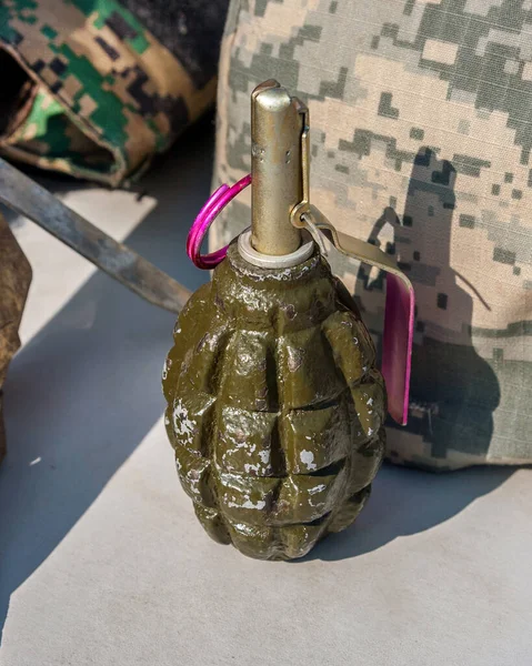 Old soviet hand grenade F1 against the background of camouflage and a helmet.