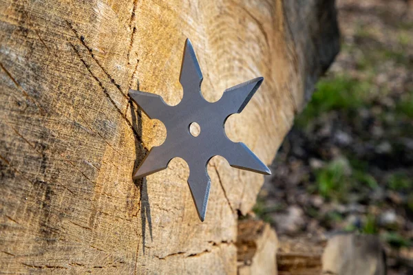 Shuriken (throwing star), traditional japanese ninja cold weapon stuck in wooden background