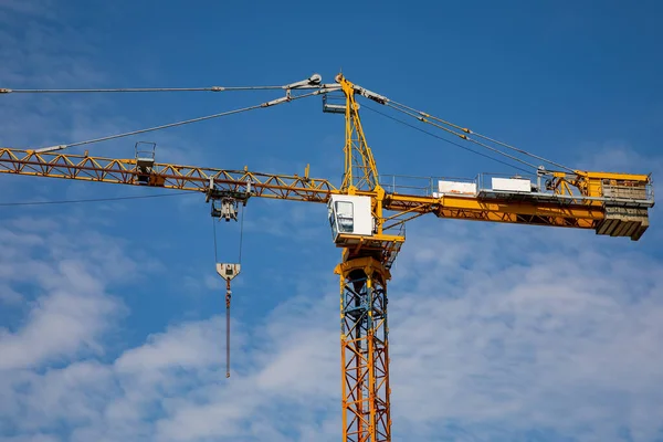 Güneşli bir günde mavi gökyüzünün arka planında inşaat vinci yük kaldırır.