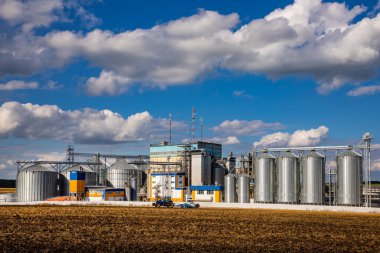 Tarım Siloları. Tahıl depolama ve kurutma tahıl, buğday, mısır, soya, ayçiçeği beyaz bulutlu mavi gökyüzüne karşı. Ekin depolama