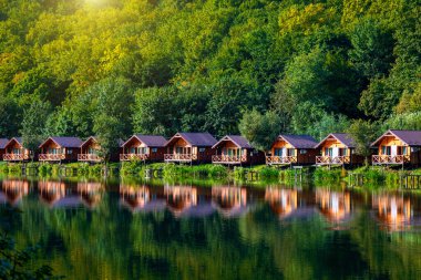 Wooden houses on the water near the forest for carp fishing. A place to relax in nature. Autumn carp fishing season.