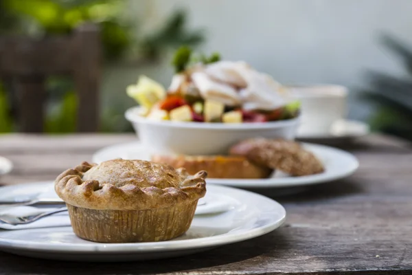 domuz pie ve yeşil salata bir bahçe ortamında eski ahşap tablo