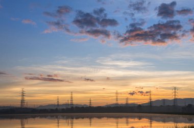 Yüksek voltaj direkleri ve yansımaları güzel sabah su ve göl manzarasında Mae Moh, Lampang, Tayland