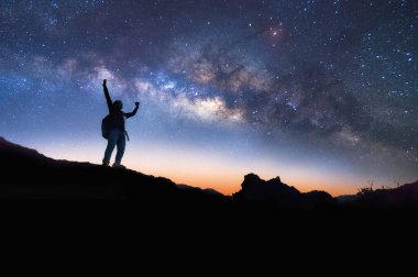 Samanyolu 'yla manzara. Gece gökyüzü yıldızlarla ve dağda duran mutlu bir adamın silüetiyle, Başarı ya da kazanan, lider konsepti. Gürültülü yüksek izo.