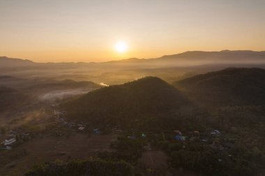 Yeşil dağlar ve yüksek voltaj direğiyle sabah ormanında sis. Pang Puai, Mae Moh, Lampang, Tayland.
