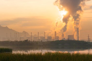 Kömür santrali ve bacadan buhar dağların ve göllerin arasında güzel bir sabah. Mae Moh, Lampang, Tayland. Bir sıra yüksek voltaj direğini doğrular.