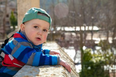 Toddler with baseball cap looking at the camera on the bridge