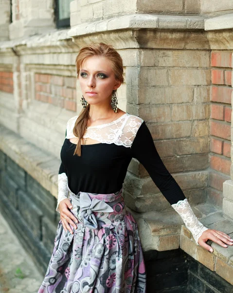 Женский портрет красоты, девушка в платье на фоне кирпичной стены старого здания — стоковое фото
