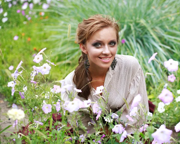 Linda chica sonriente disfrutar del día de verano en el jardín de flores —  Fotos de Stock