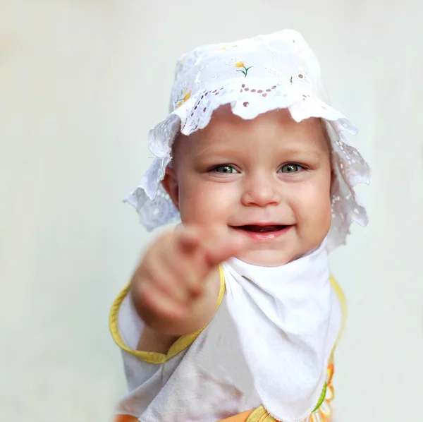 Smiling baby girl pointing a finger, on white background. Focused on her face. — Stock Photo, Image