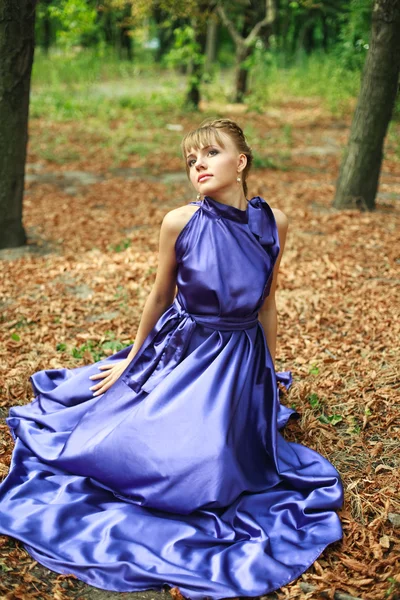 Giovane ragazza attraente in abito lungo viola al parco — Foto Stock