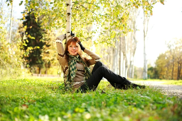 Woman resting under a birch tree in autumn park — Stock Photo, Image