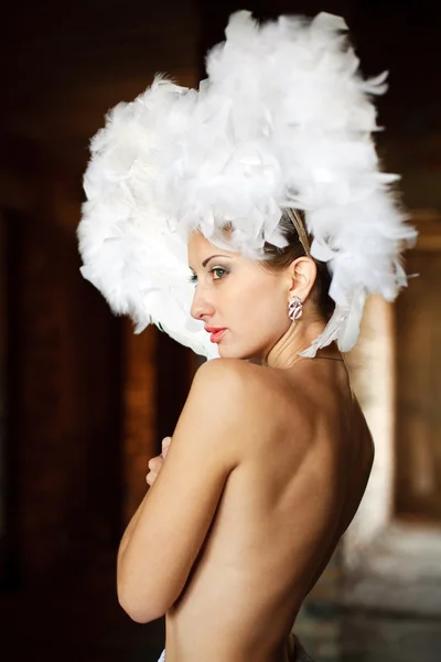 Portrait of beautiful girl with feathers on her head in a dark room — Stock Photo, Image