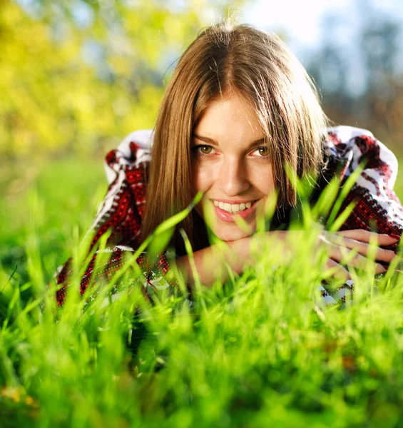 Muito sorridente jovem deitada na grama verde de perto, no parque de verão . — Fotografia de Stock