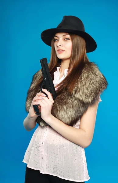 Uma jovem séria com um chapéu preto com uma arma na mão, em — Fotografia de Stock