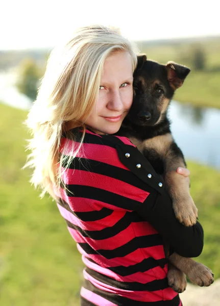 Teen ragazza che tiene un cucciolo di pastore tedesco all'aria aperta, retroilluminato — Foto Stock