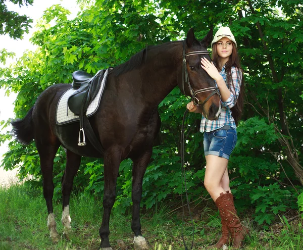 Außenporträt der schönen Cowgirl mit Pferd in grün — Stockfoto